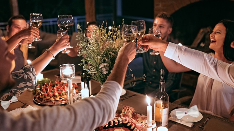 Image of a group around a dining table raising their wine glasses at a shared meal.