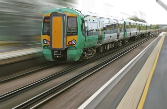 Image of a train on the tracks approaching a platform with blurred background to show movement.